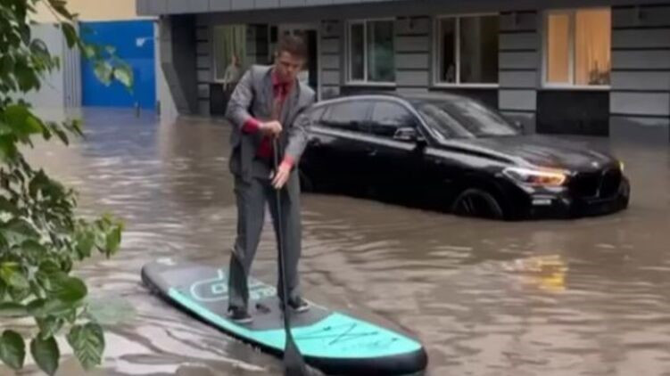 В Киеве парень в костюме и с веслом плыл по затопленной дороге, видео