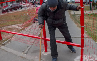 На Оболони на тротуаре возле метро поставили забор, но местные жители пробили дыру и пролазят сквозь нее