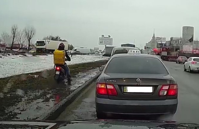 В Киеве курьер на мопеде по газону и грязи объехал пробку, видео